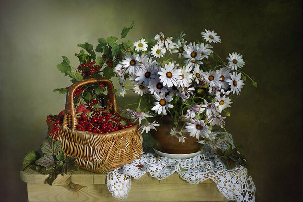 Bouquet of daisies in a clay vase and ripe currants on the table