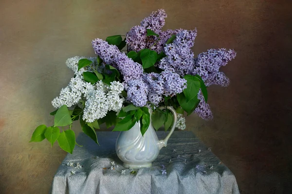 A bouquet of beautiful Lilac in a vase on the table .