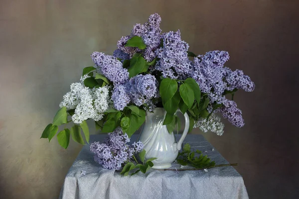 A bouquet of beautiful Lilac in a vase on the table .