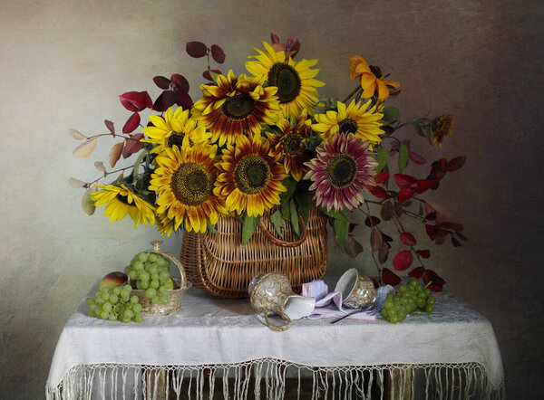 Still life with grapes and sunflowers on the table.
