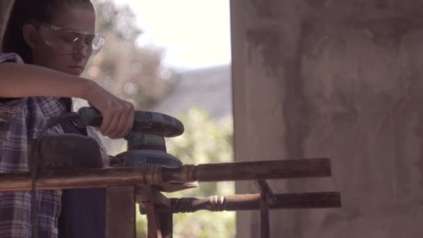 Дівчина відновлює старі меблі, працює шліфувальною машиною — стокове відео