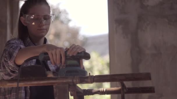 Das Mädchen repariert die alten Möbel, arbeitet an der Schleifmaschine — Stockvideo