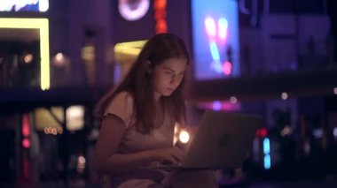 Kız gece şehirde bir dizüstü bilgisayar ile ofis dışında çalışır