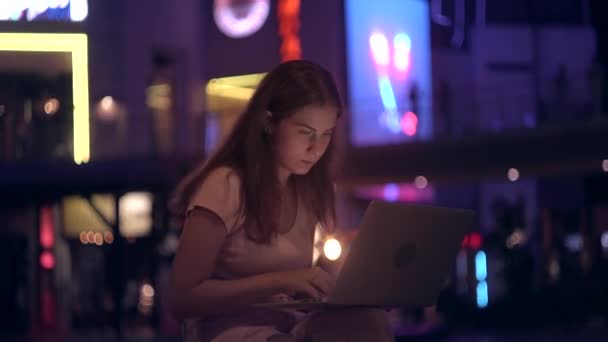 Το κορίτσι που λειτουργεί έξω από το γραφείο με ένα laptop στην πόλη το βράδυ — Αρχείο Βίντεο