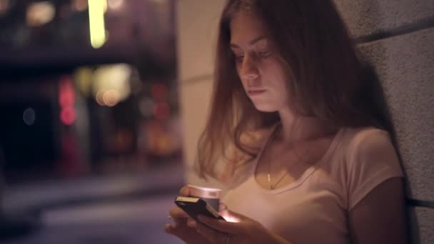 Porträtt av en flicka med kaffe och en smartphone i en natt stad — Stockvideo