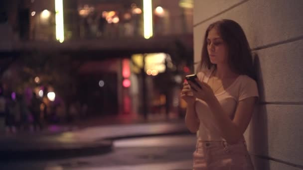 Retrato de uma menina com café e um smartphone em uma cidade noturna — Vídeo de Stock