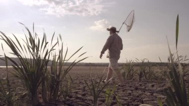 Balıkçı kuru bir gölün kıyısında yürür