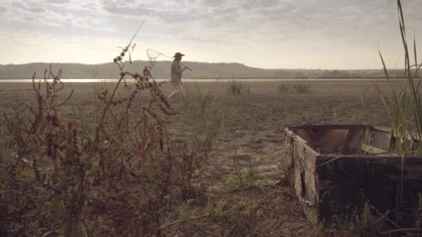 El pescador va al lago por la mañana temprano. — Vídeo de stock