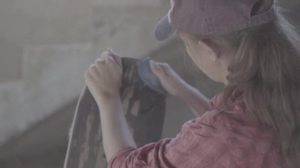 Close-up of a girl in the workshop polished with sandpaper skateboard — Stock Video