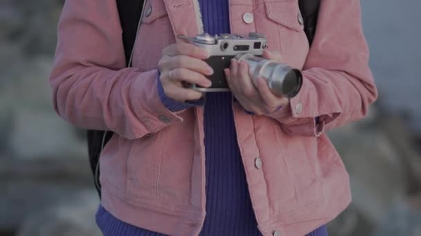 Meisje in koptelefoon neemt een foto van de zee zonsondergang op haar vintage camera — Stockvideo