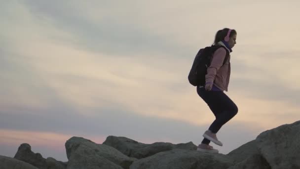 Mladá cestovatelka kráčí po hřebeni. Prudká hora, nabízející krásný výhled na oceán při západu slunce — Stock video