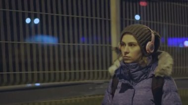 Kablosuz kulaklıklı kız, gece şehrine gidiyor.