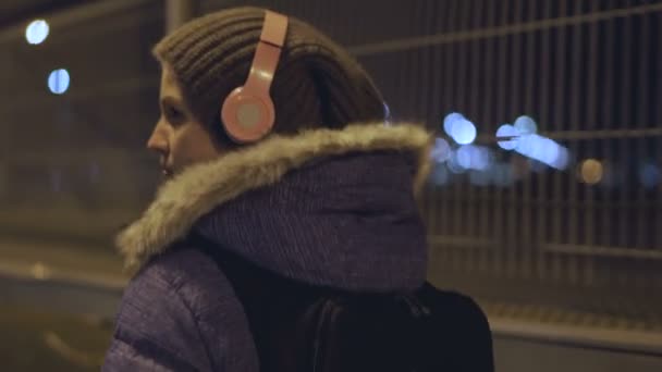 La chica con auriculares inalámbricos, va a la ciudad nocturna — Vídeos de Stock