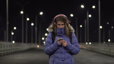 Akıllı telefondaki kız geceleri şehirde, sosyal ağlarda konuşuyor.