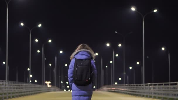 Seorang gadis dalam jaket musim dingin berjalan melalui sepi, kota malam — Stok Video