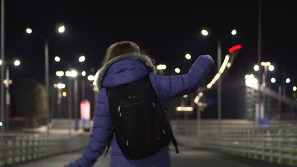 겨울 재킷을 입은 소녀가 러시아 소치의 밤 도시, 장소에서 춤을 추고 있습니다. — 비디오