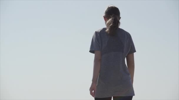 En sport flicka går längs strandpromenaden längs havsstranden på en solig dag — Stockvideo