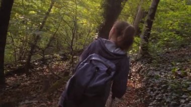 Sırt çantalı bir turist orman yolunda yürüyor. Etrafına bakıyor ve ormanın güzelliğine hayran.