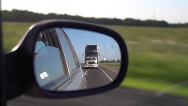 Lastbilen speglas i sidobackspegeln. Utsikt från bilfönstret — Stockvideo