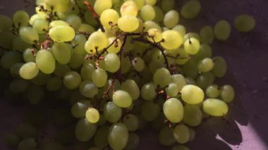 Masada güneş ışığında bir demet yeşil üzüm ve biraz su. Güneş parlıyor