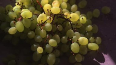 Masada güneş ışığında bir demet yeşil üzüm ve biraz su. Güneş parlıyor