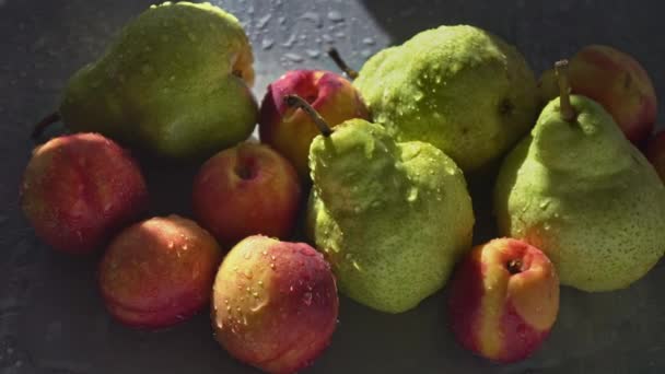 Szaftos gyümölcsök körte és őszibarack az asztalon a napfényben és fröccsenő víz — Stock videók
