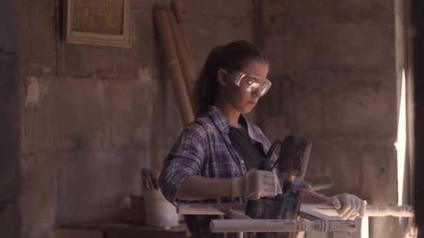 Dziewczyna stolarz naprawy zabytkowych mebli za pomocą szlifierki — Wideo stockowe