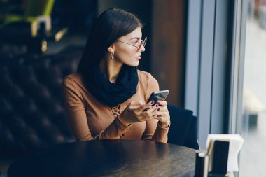 Esmer kız restoranda telefon kullanıyor.