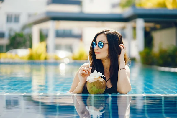Μελαχρινή κοπέλα τρώει φρούτα δίπλα στην πισίνα — Φωτογραφία Αρχείου