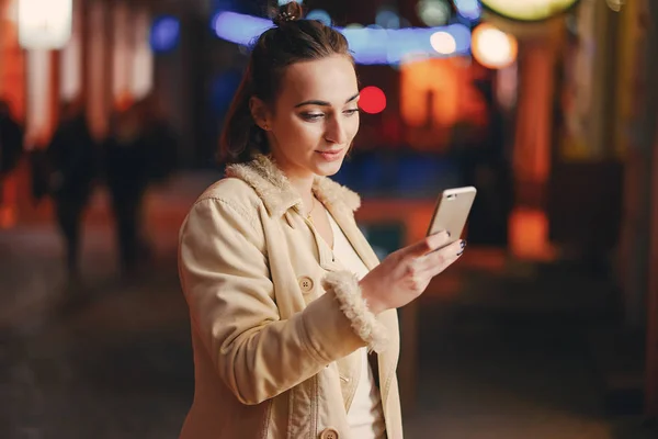 Lány ellenőrzi a telefonját odakint éjszaka — Stock Fotó