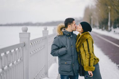Güneşli bir kış gününde parkta yürüyen mutlu çift.