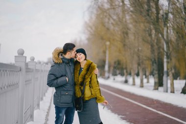 Güneşli bir kış gününde parkta yürüyen mutlu çift.