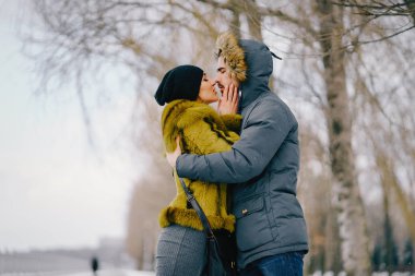 Güneşli bir kış gününde parkta yürüyen mutlu çift.