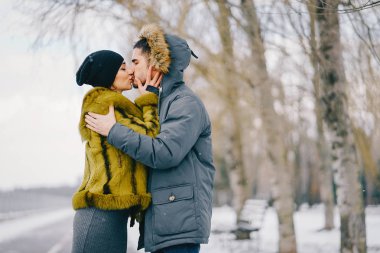 Güneşli bir kış gününde parkta yürüyen mutlu çift.