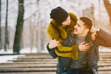 Güneşli bir kış gününde parkta yürüyen mutlu çift.