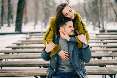 Güneşli bir kış gününde parkta yürüyen mutlu çift.