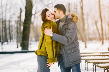 Güneşli bir kış gününde parkta yürüyen mutlu çift.