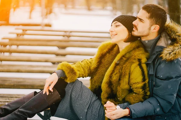 Güneşli bir kış gününde parkta yürüyen mutlu çift.