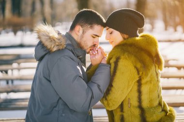 Güneşli bir kış gününde parkta yürüyen mutlu çift.
