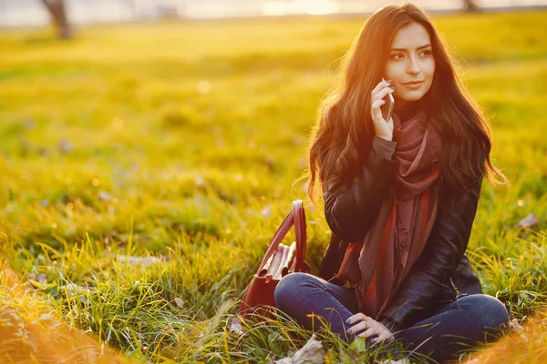 Brunette meisje met behulp van de telefoon terwijl in het park — Stockfoto