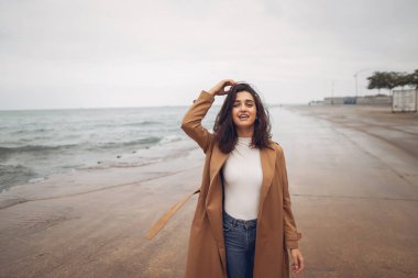 Genç kız sahilde yürüyor.