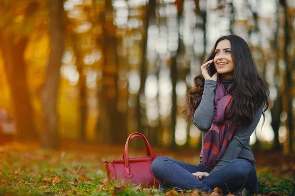 Брюнетка дівчина використовує телефон, перебуваючи в парку — стокове фото