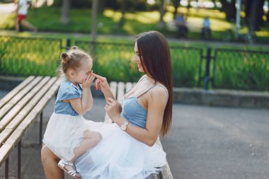 küçük kızıyla birlikte parkta oturan bir güzel genç ince ve uzun saçlı anne