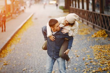 Güneşli bir sonbahar gününde şehirde yürüyen mutlu bir çift.