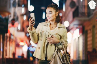 Kız gece dışarıda telefonunu kontrol ediyor.