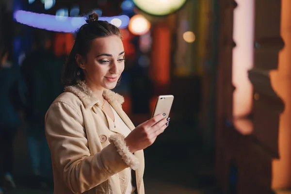 Lány ellenőrzi a telefonját odakint éjszaka — Stock Fotó