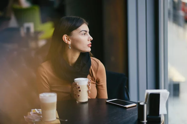 Brunetka dívka pomocí telefonu, zatímco v restauraci — Stock fotografie