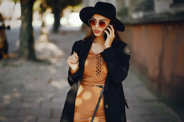 Ragazza elegante a piedi attraverso la città durante l'utilizzo del telefono — Foto Stock