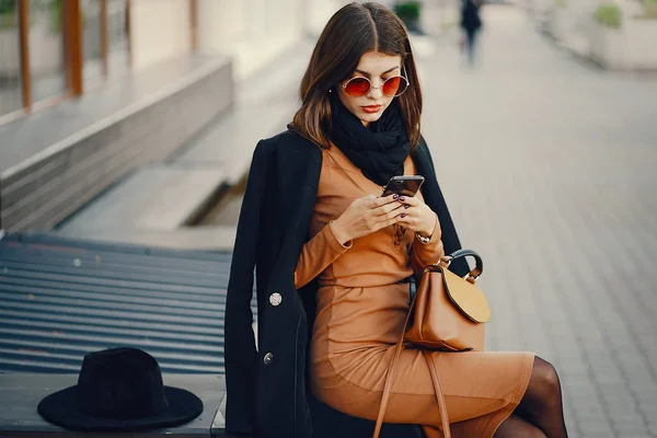 Stílusos lány sétál a városban, miközben használja a telefonját — Stock Fotó