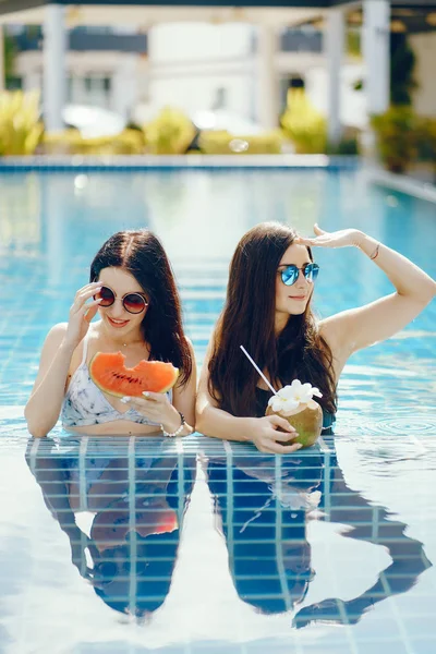 Duas meninas com frutas na piscina — Fotografia de Stock